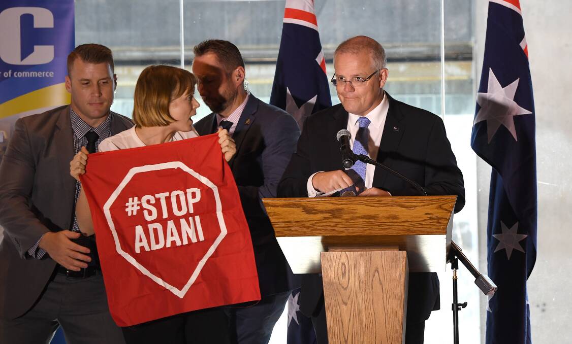 A Stop Adani protester takes to the stage where Australian Prime Minister Scott Morrison was making a speech at a the Valley Chamber of Commerce business luncheon in Brisbane on Monday. Photo: AAP Image/Dave Hunt
