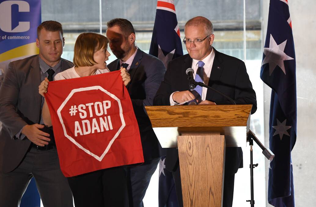 A Stop Adani protestor is removed from the stage where Australian Prime Minister Scott Morrison was making a speech in Brisbane on Monday. Photo: AAP Image/Dave Hunt