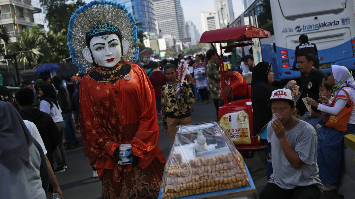 A street busker in a traditional giant puppet called 'ondel-ondel' in Jakarta as the world's third-largest democracy is gearing up to hold its legislative and presidential elections. Photo: AP
