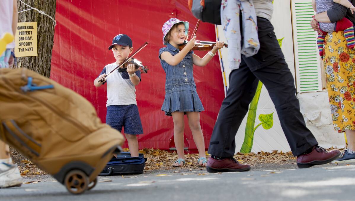 Gilbert Clipshan, 4, and Audrey Clipshan, 6, from Bathurst take their music to the sidewalks of the National Folk Festival. Photo: Sitthixay Ditthavong