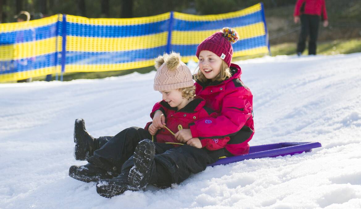 Sophie Kerr, 9, and Lucy Kerr, 5, try their hand at tobogganing at the Corin Forest snow play area on Saturday. Photo: Dion Georgopoulos