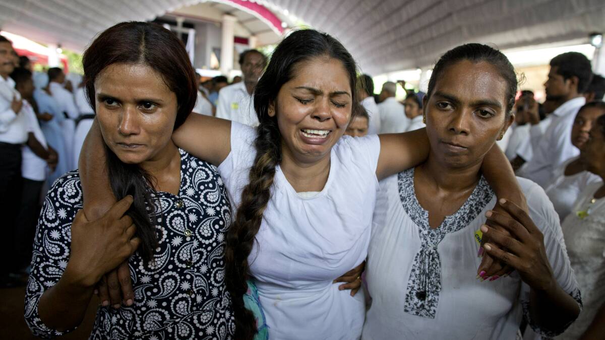 A grieving woman is supported during a funeral service for Easter Sunday bomb blast victims. Photo: Gemunu Amarasinghe/AP
