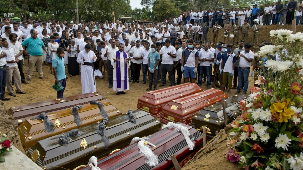 A priest conducts religious rituals during a mass burial for Easter Sunday bomb blast victims in Negombo, Sri Lanka. Photo: AP