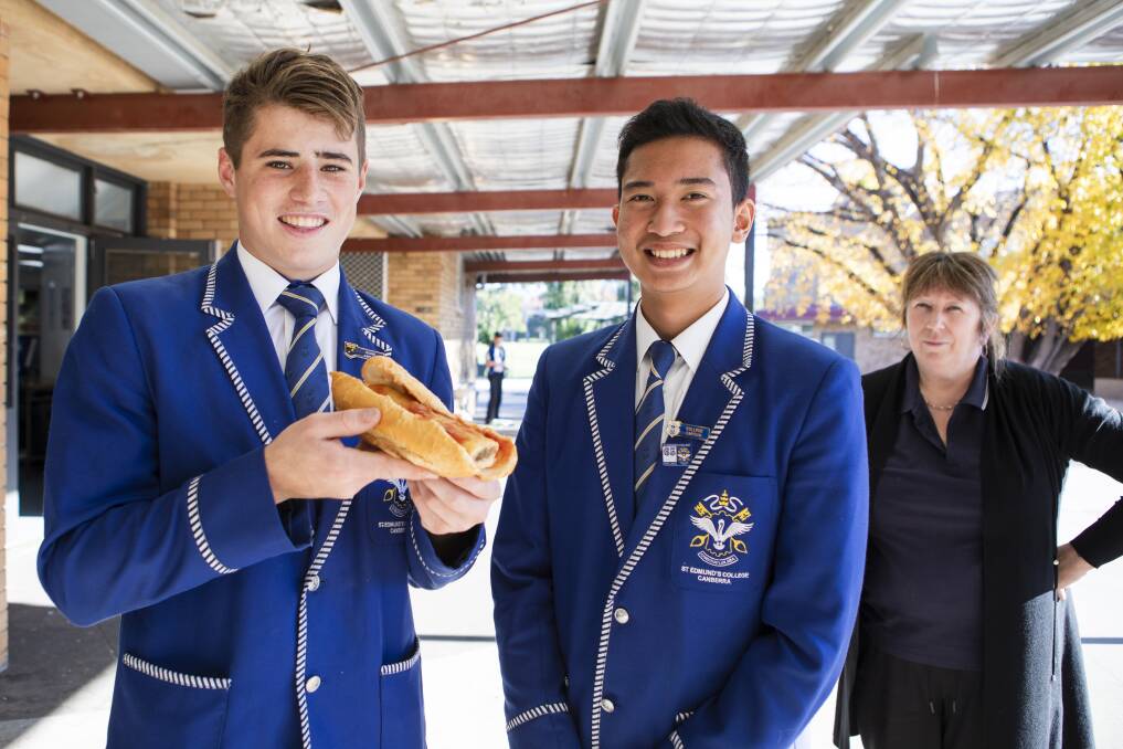 St Edmund's College students Eamon McCoola, 17, and Symon Referzo, 16, with the iconic sausage roll in a bun and canteen manager, Pam Knight. Picture: Jamila Toderas