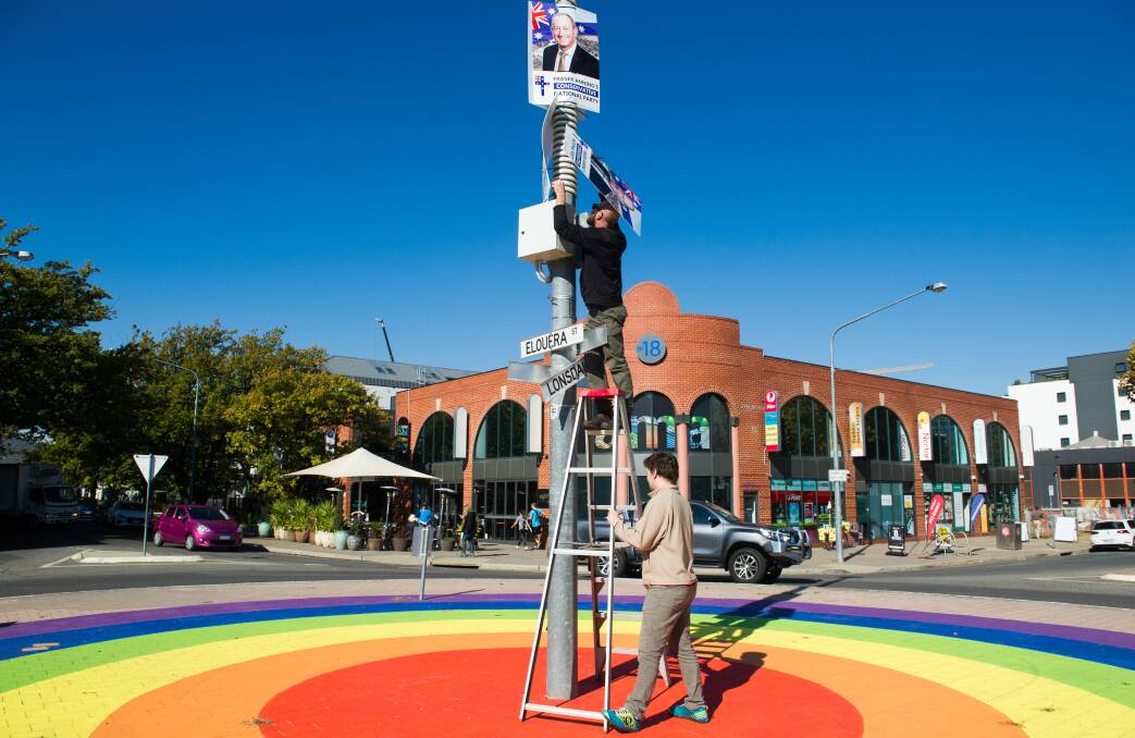 Unnamed local residents take down Fraser Anning corflutes placed in the middle of the rainbow roundabout in Braddon. Picture: Elesa Kurtz