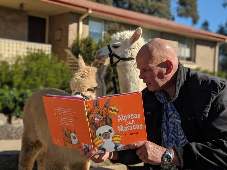Nils Lantzke, of Giralang, reading Alpacas with Maracas with Hercules (back) and Paprika, ahead of National Simultaneous Storytime on Wednesday. Picture: Megan Doherty