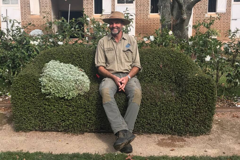 Head gardener Rick Shepherd takes a break on the hedge seat, complete with cushion. Picture: Supplied