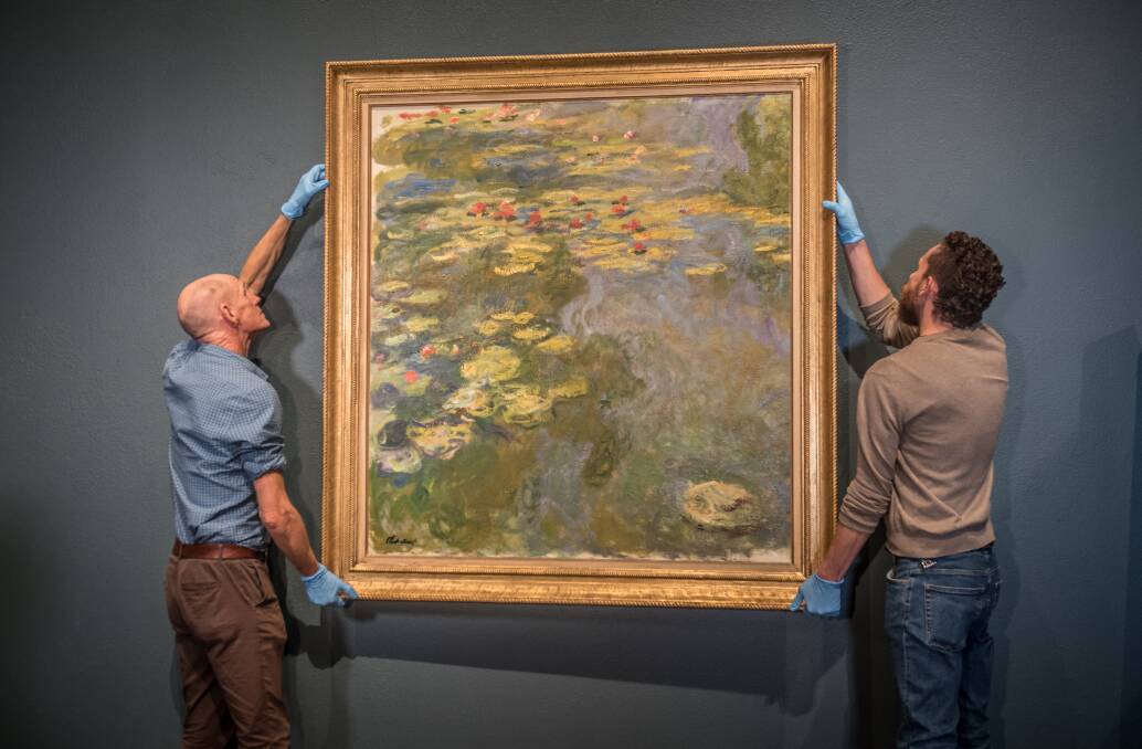 National Gallery of Australia installers Ben Taylor (left) and Chris Burton hang Claude Monet's 'Waterlillies'. Picture: Karleen Minney.