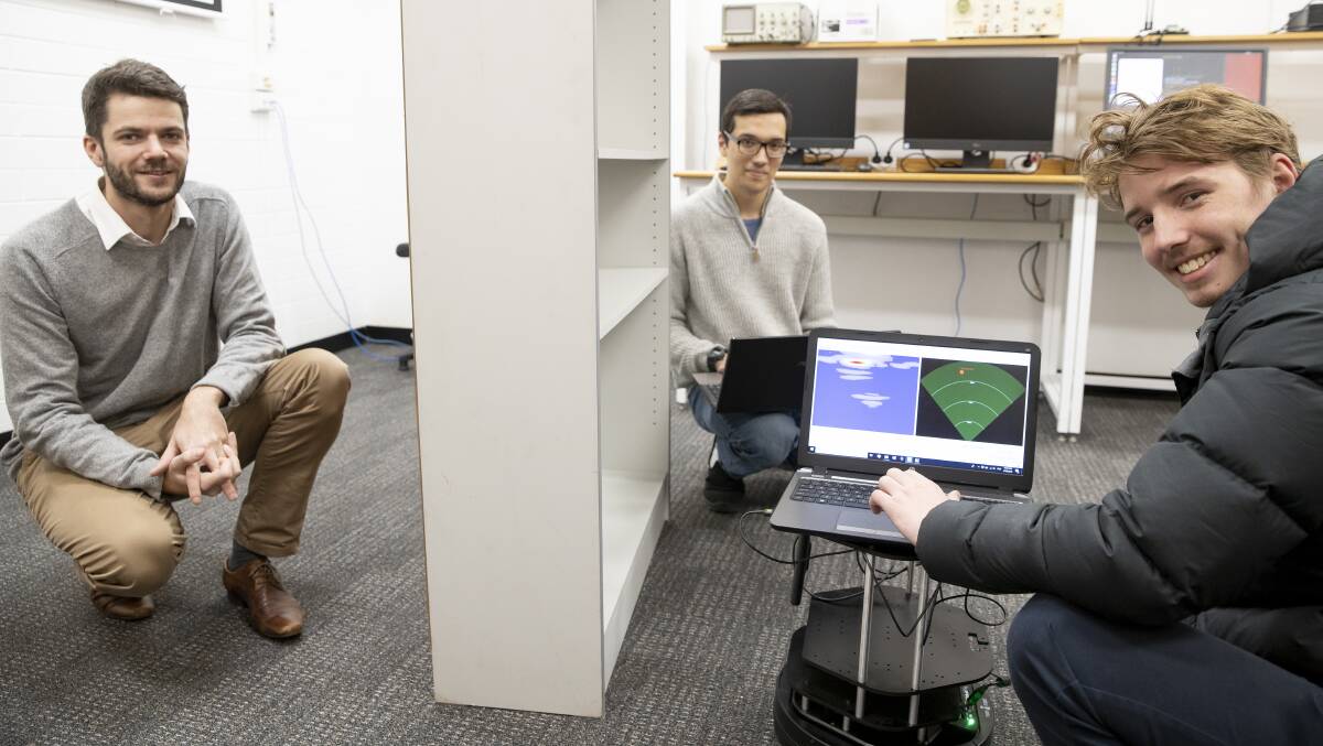 University of Canberra engineering honours students Adam Hoad and Daniel Mustaine (right) scan through a bookcase to locate fellow student Edward McCarthy. Picture: Sitthixay Ditthavong