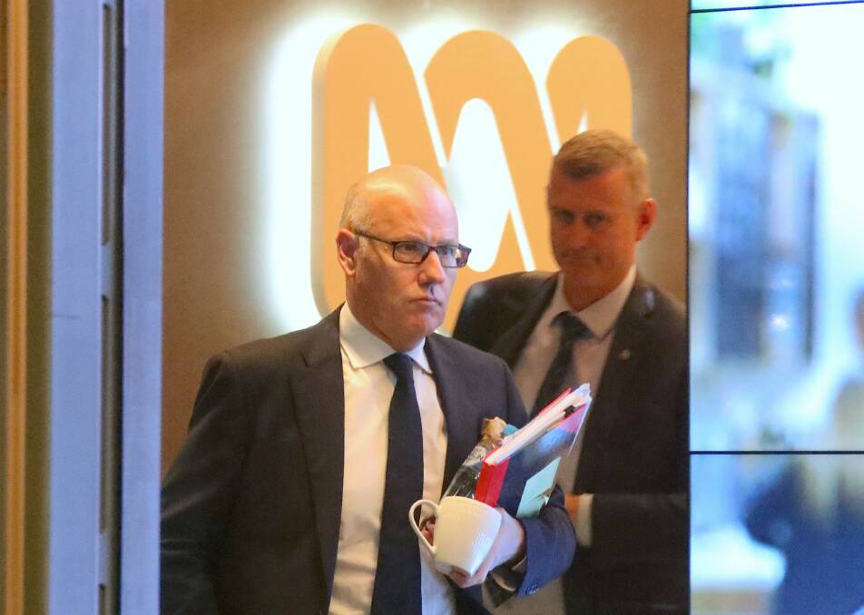 Executive Editor of ABC News John Lyons (left) is followed by an Australian Federal Police officer as they walk out the main entrance to the ABC building at about 8.20pm. 