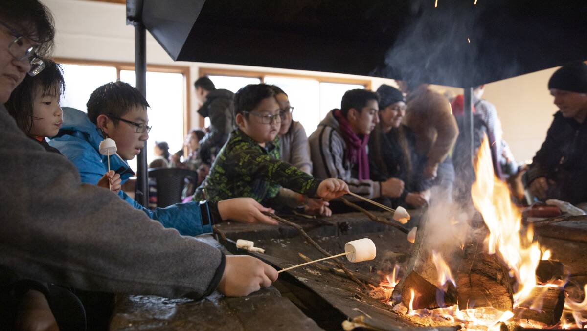 Visitors to Corin Forest toast marshmallows and warm up by the fire on Monday. Picture: Sitthixay Ditthavong