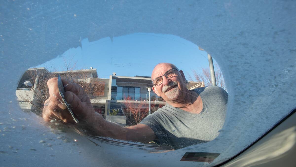 Gary Cairns of Kingston scrapes the ice from his windscreen on a frosty Canberra morning. Picture: Karleen Minney.