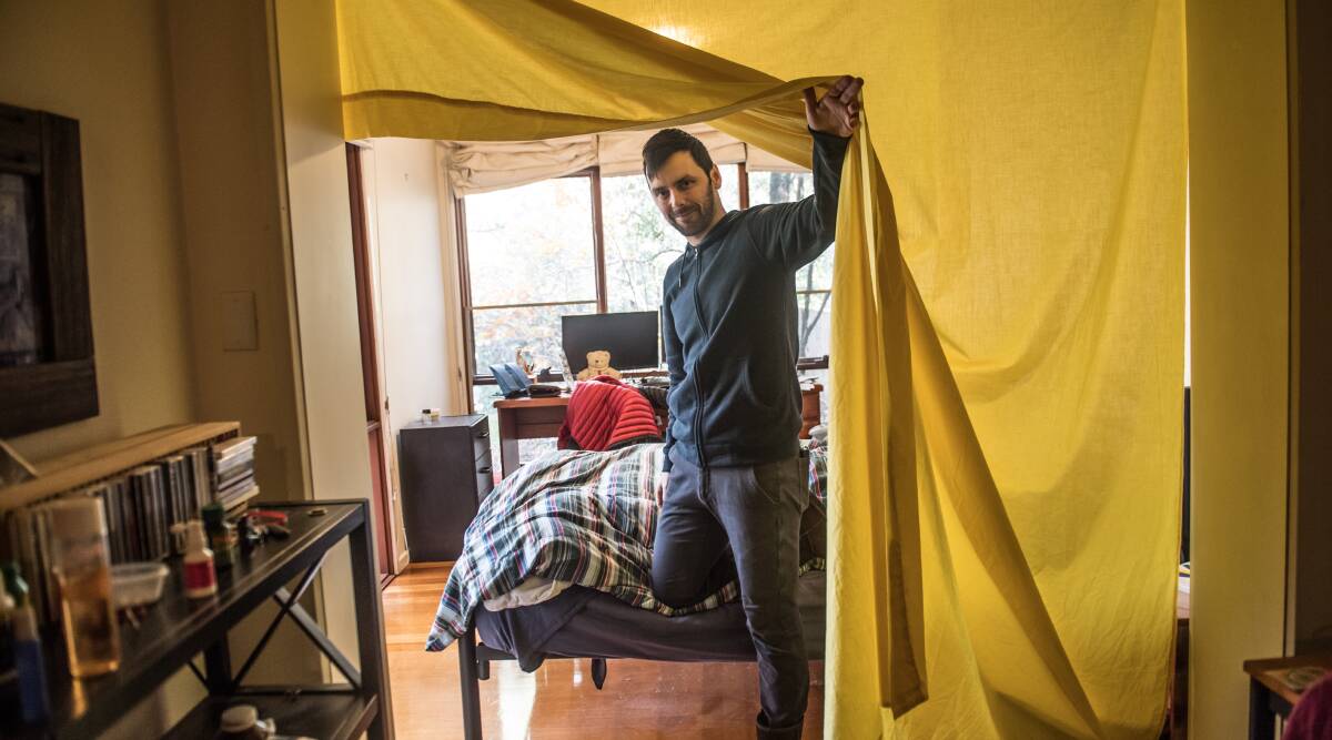 Tom Swann, who uses do-it-yourself methods - like masking tape around windows, and hanging fabric on doorways - to stop cold draughts coming into his Campbell sharehouse. Picture: Karleen Minney