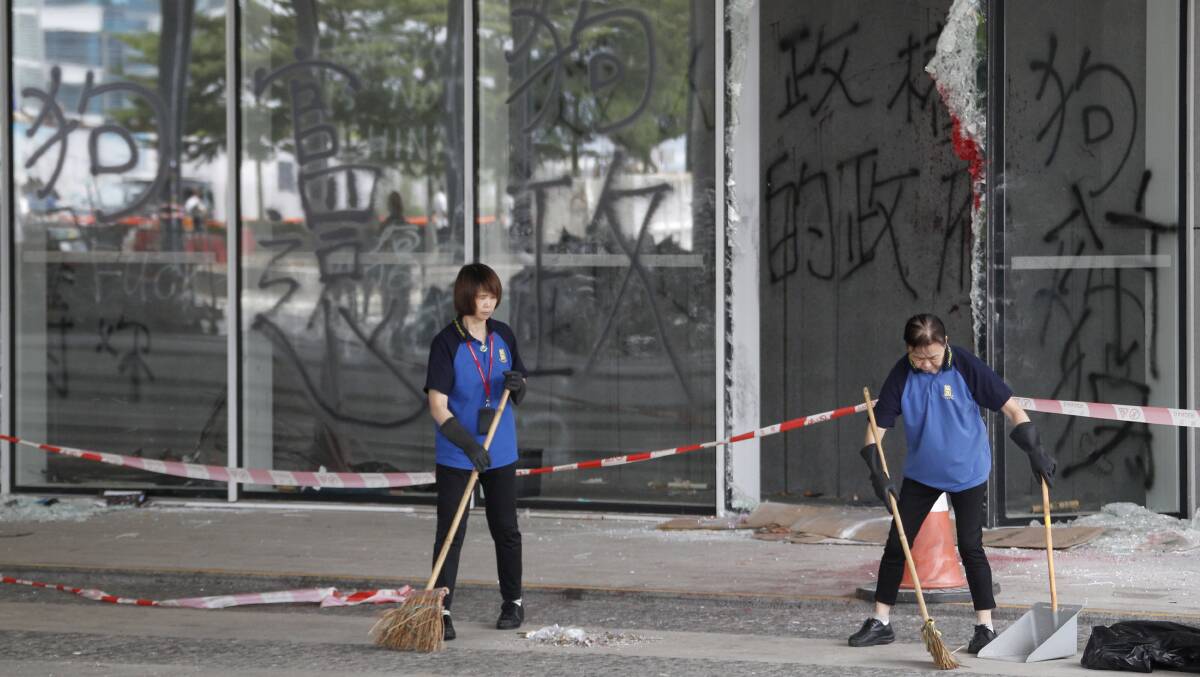 Workers clean the area near broken window panels and graffiti which reads "Dog official, Dog government" at the Legislative Council in Hong Kong. Picture: AP