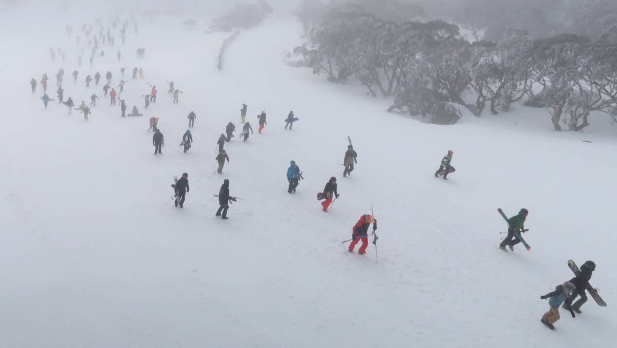 Hundreds of skiers and snowboarders walk up the mountain after a blizzard shuts down the Perisher chairlifts on Sunday. Picture: Alex Ellinghausen