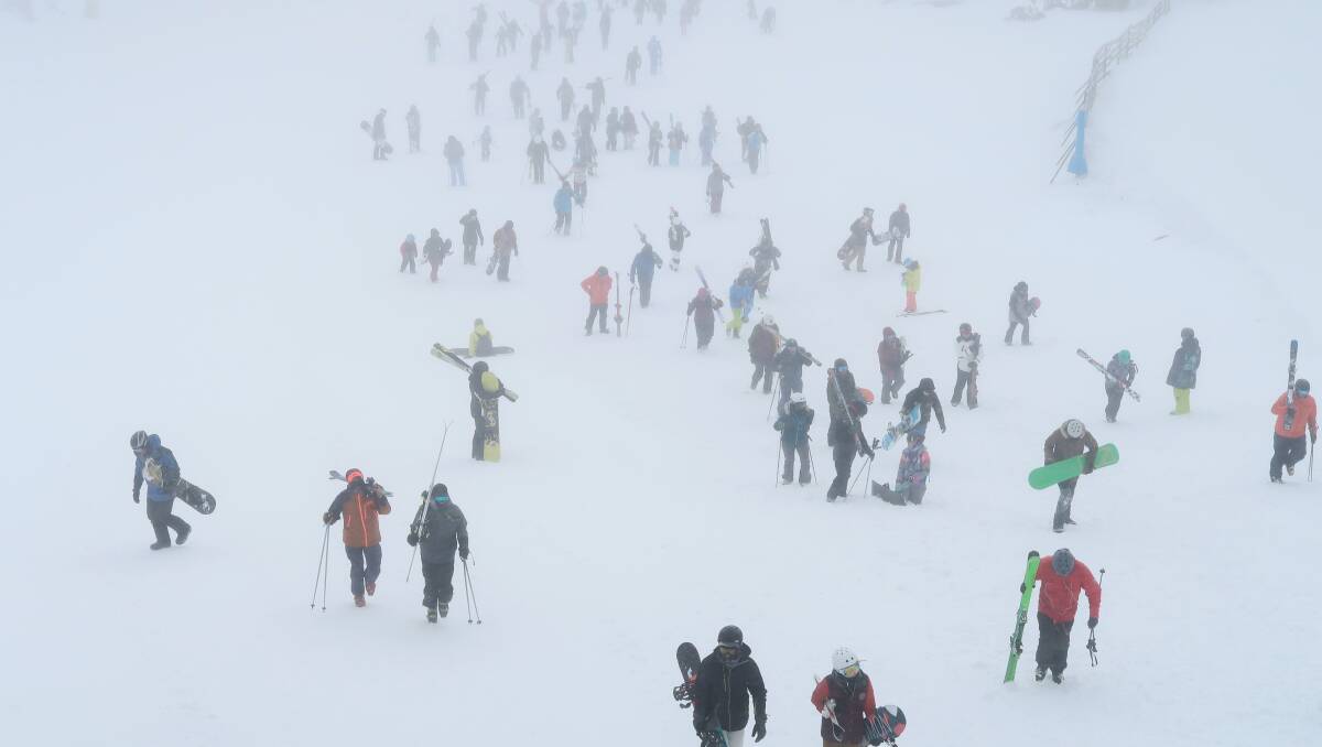 Hundreds of skiers and snowboarders walk up the mountain after a blizzard shuts down the chairlifts, at the Snowy Mountains on Sunday. Picture: Alex Ellinghausen