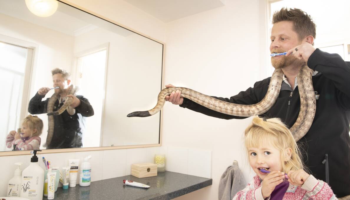 Snake catcher Gavin Smith with his four-year-old daughter Sylvie, and Charlotte the black-headed python. Dr Smith wants to improve people's perceptions of snakes. Picture: Sitthixay Ditthavong