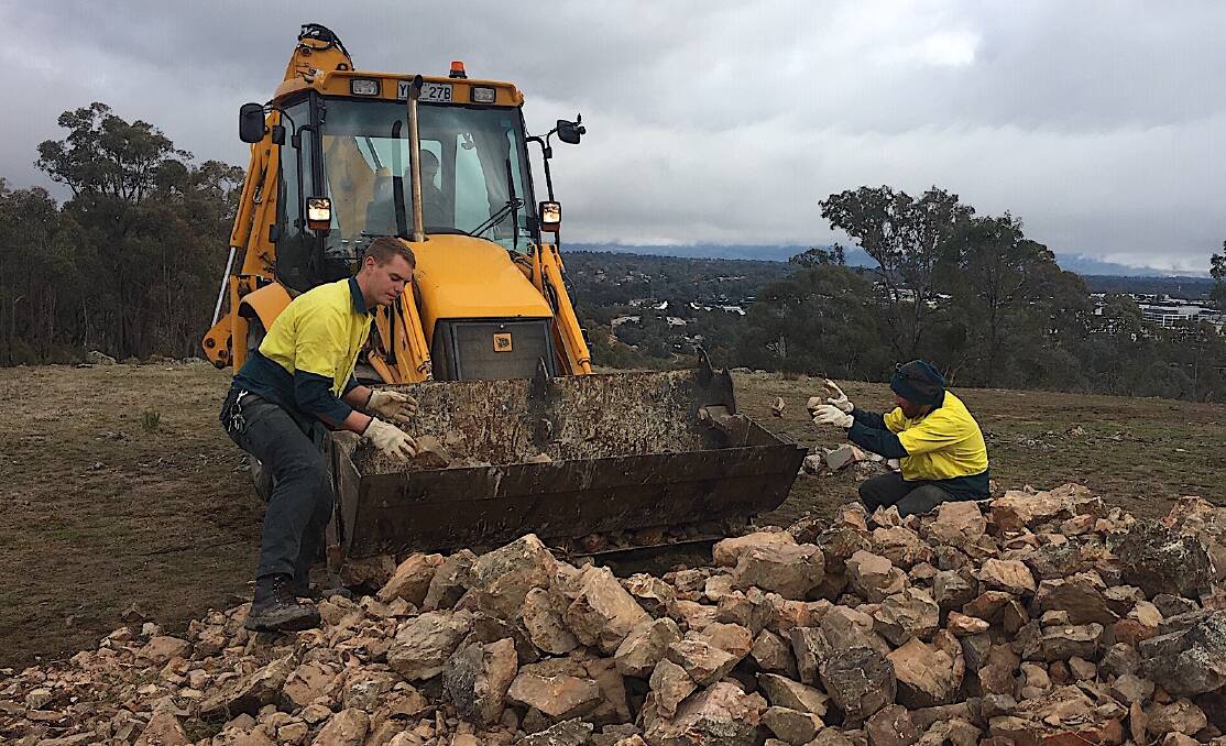 ACT Parks and Conservation Service field offices dismantle the rock cairns at Gossan Hill. Picture: Michelle Nairn