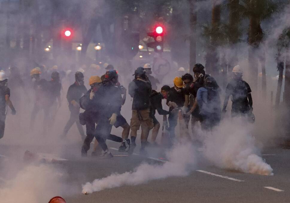 Protesters use traffic cones to cover the tear gas canisters fired by riot policemen during the anti-extradition bill protest in Hong Kong. Picture: AP