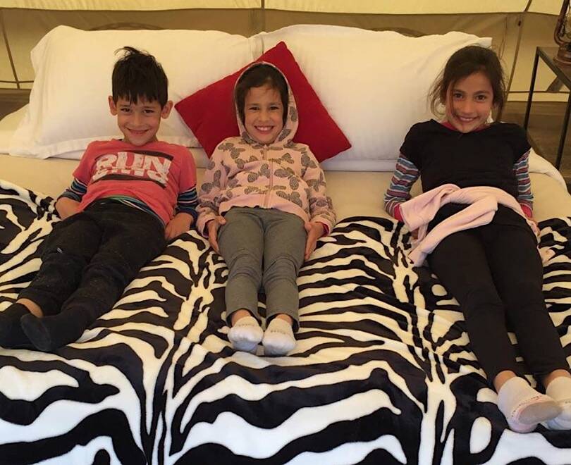 Marcus Singh, with his sisters Laila and Aanya, test out the king-sized bed in their tent at Tidbinbillas Pop-Up Wilderness Camps. Picture: Supplied