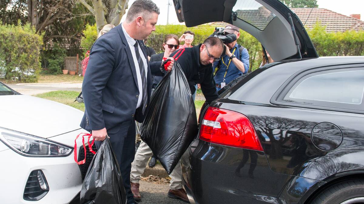 Australian Federal Police officers load garbage bags of evidence into a car. Picture: Elesa Kurtz