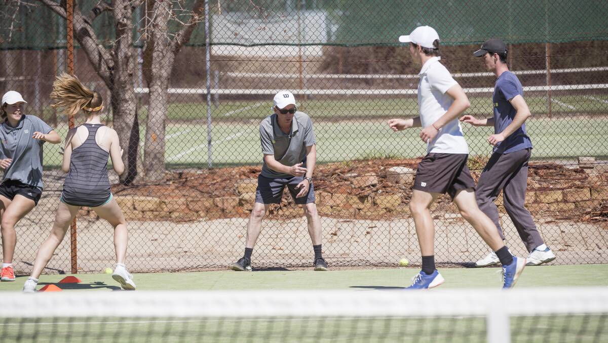 Canberra School of Tennis founder Mark Walton leads some students through a warm up cardio session at Weston Creek. Picture: Sitthixay Ditthavong