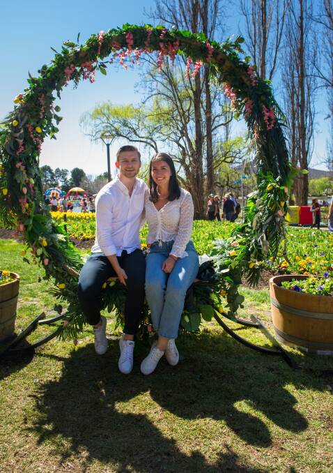 Hayden Buchanan and Cristina O'Gorman, from Sydney, sit in large floral wreath created for Floriade. Picture: Elesa Kurtz