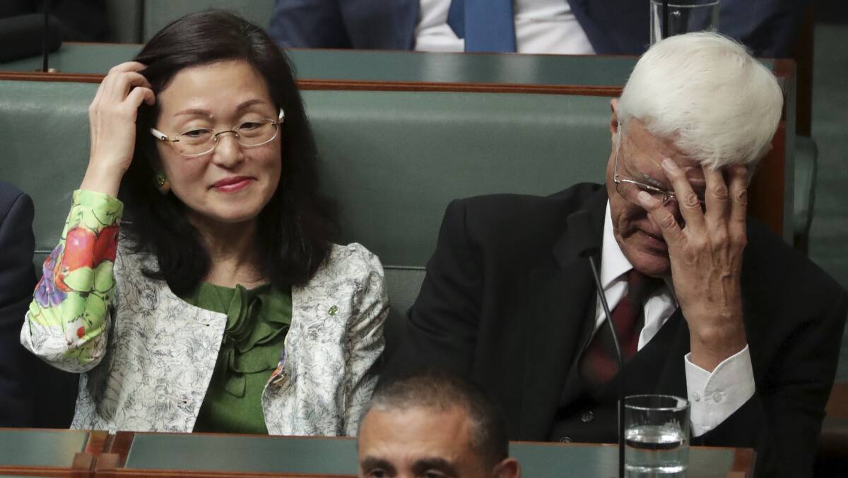 Crossbench MP Bob Katter covers his face while sitting next to Liberal MP Gladys Liu in Parliament on Monday. Picture: Alex Ellinghausen