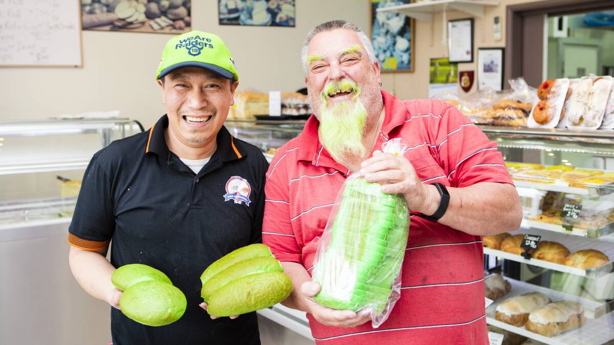 Vina Bakery owner Quan Nguyen shows off his green bread and rolls to Raiders fanatic Mick Lennon of Kambah. Picture: Jamila Toderas