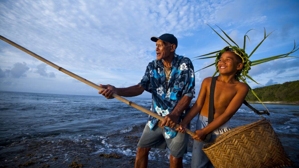Islanders fish from the rocks with a bamboo rod.