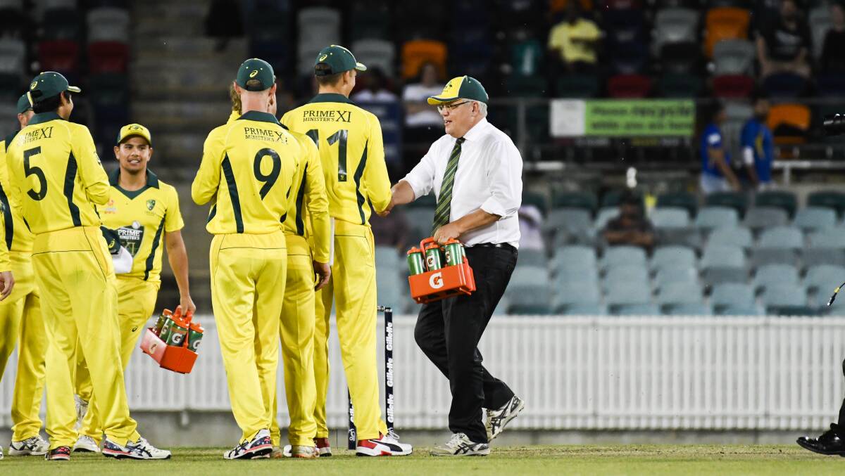 Prime Minister Scott Morrison (right) carries the drinks out to the Prime Minister's XI during their match against Sri Lanka at Manuka Oval last year. Picture: Dion Georgopoulos