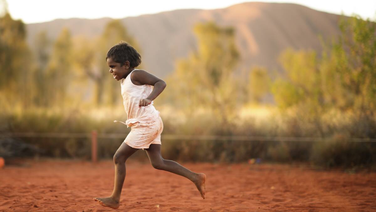 A boy plays while waiting for performances to start during a community event to celebrate to closure of the Uluru climb on Sunday. Picture: Alex Ellinghausen