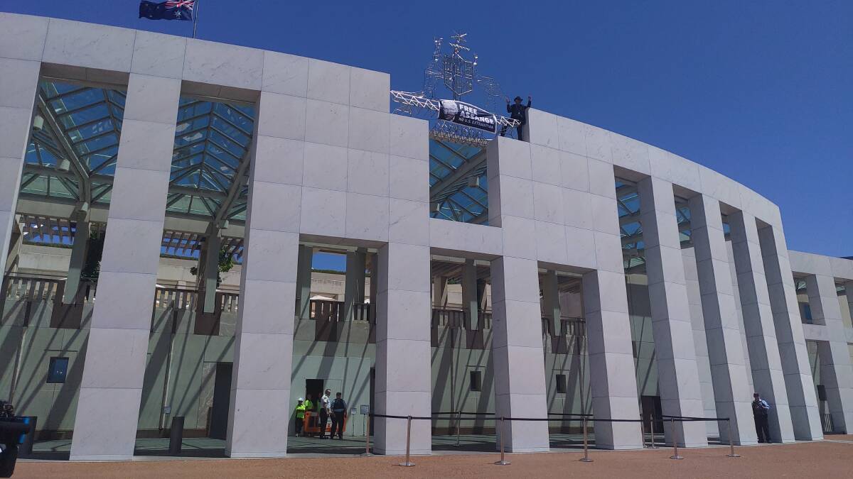 A protester on the roof of Parliament House on Monday. 