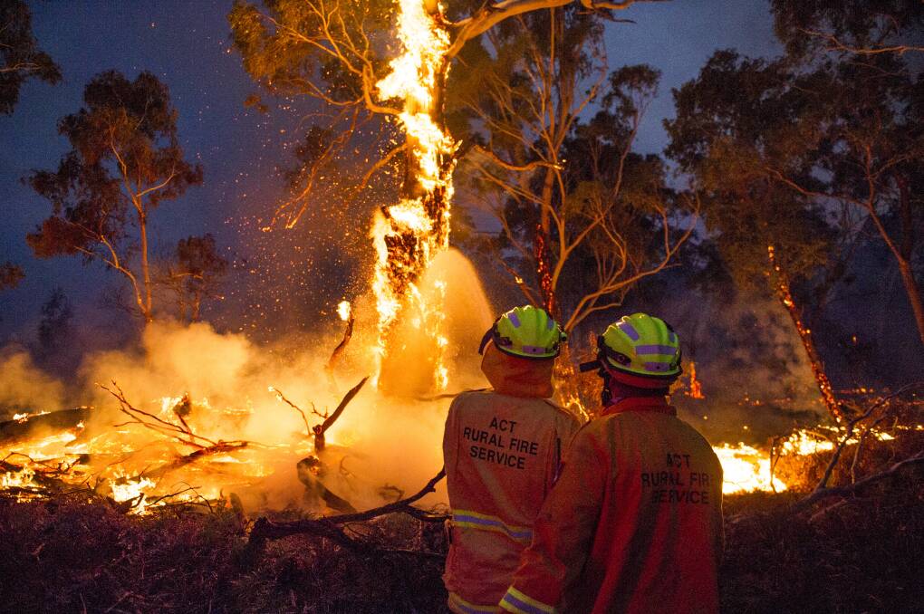 Firefighters work to put out fires at the edge of the North Black Range bushfire near Braidwood on Thursday night. Picture: Dion Georgopoulos