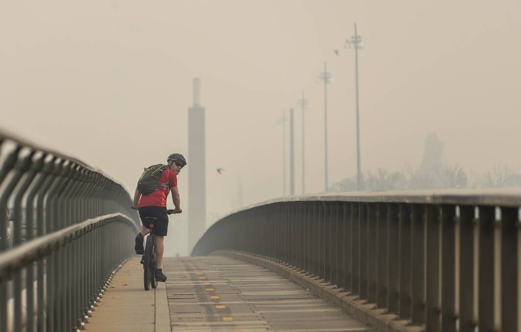 A cyclist is seen on the Commonwealth Avenue bridge on Tuesday afternoon as the Civic air quality station reported a hazardous air quality index. Picture: Sitthixay Ditthavong