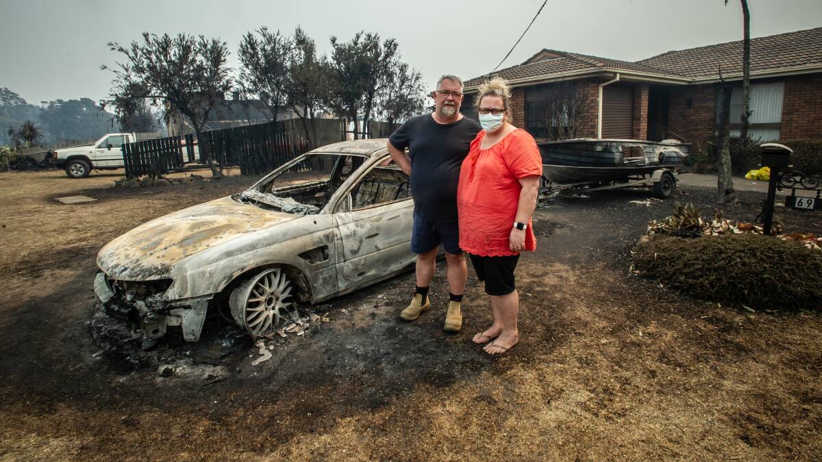 Mark Peters and Kim Harper in front of the only house in their street to survive, although they lost a car and a boat. Picture: Karleen Minney
