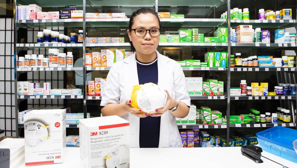 Canberra pharmacist Christine Uy demonstrates a P2 mask. Picture: Jamila Toderas