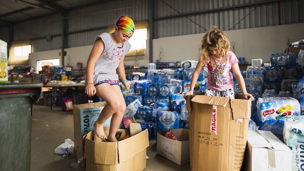 India, 10, and Klancy Bonomi, 8, help crush cardboard boxes at the Cobargo relief centre. Picture: Dion Georgopoulos