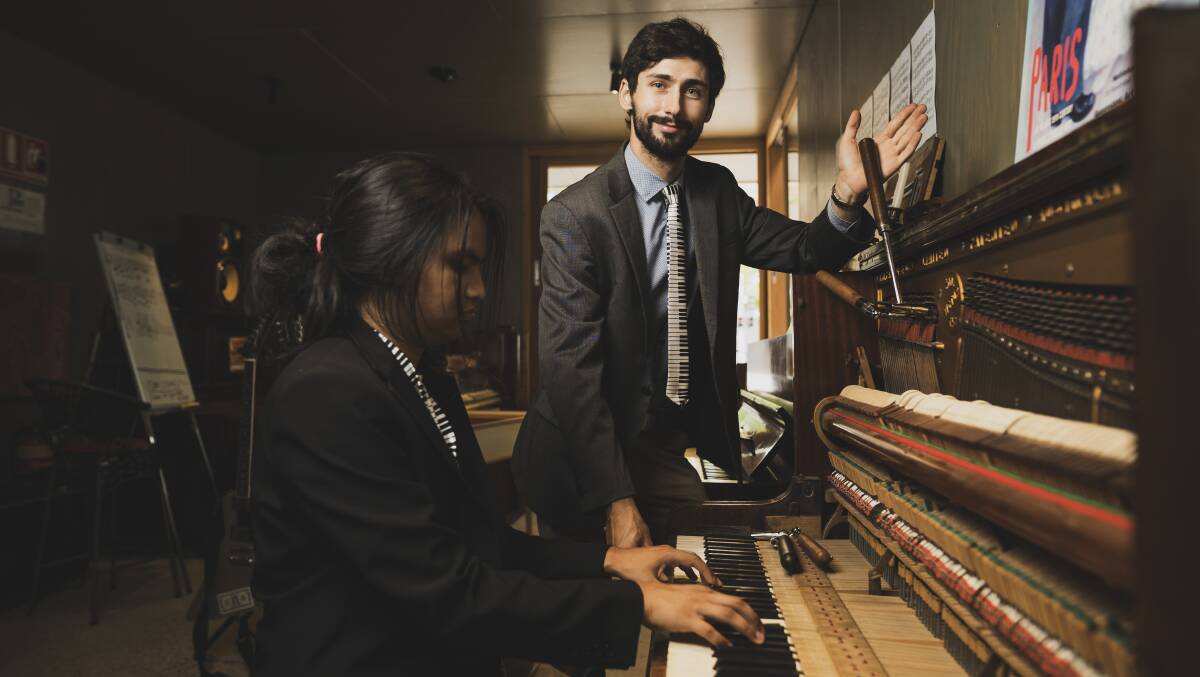 Mathias Mustillo, right, with his hand on a tuning wrench, while William Mon plays at the Piano Rescuer's Allara Street kiosk. Picture: Dion Georgopoulos