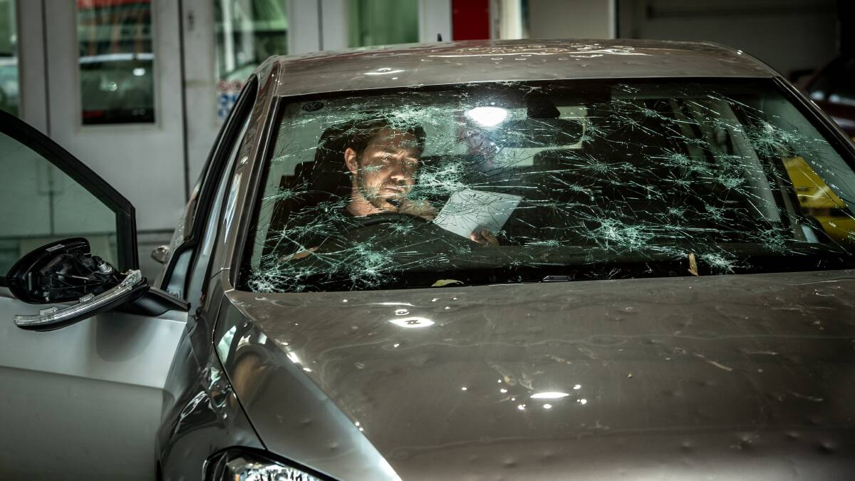 Fyshwick's The Dent Brothers business owner Isaac Dunn inspects a smashed vehicle after the hailstorm. Picture: Karleen Minney.