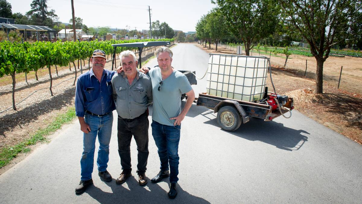 Pialligo Estate grounds maintenance and fire warden Greg Ring, head horticulturist John Sanderson and general manager Scott Taylor with their cube of water that helped protect the property from fire in Pialligo on Thursday. Picture: Elesa Kurtz