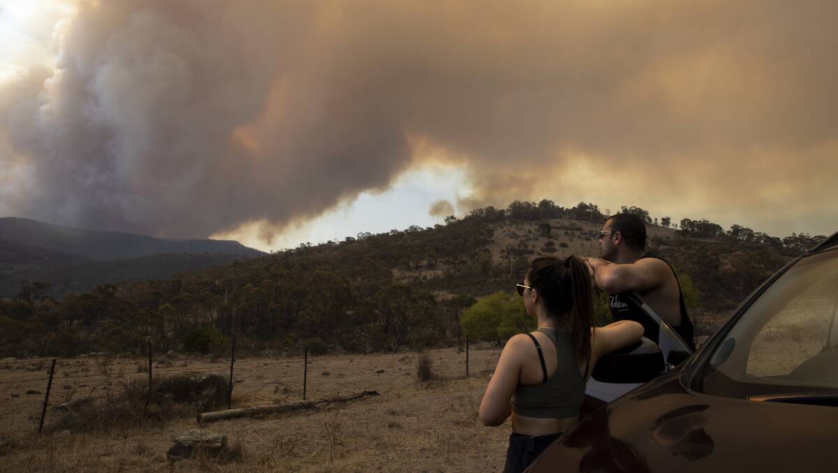 Amelia Stevenson and Jamahl Bakri from Harrison watch a smoke plume from a bushfire that started in Namadgi National Park on Monday afternoon. Picture: Sitthixay Ditthavong