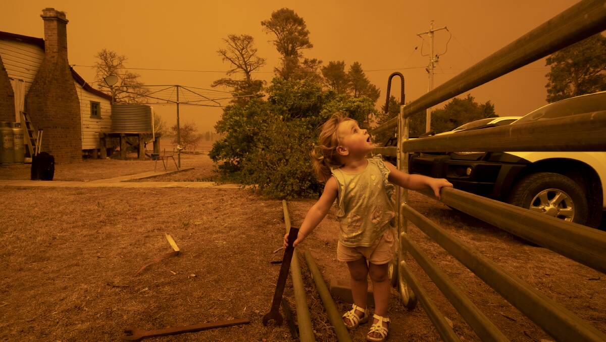 One-year-old Chelsea Povey watches as the sky darkens from the Clear Ridge bushfire in February. Picture: Sitthixay Ditthavong