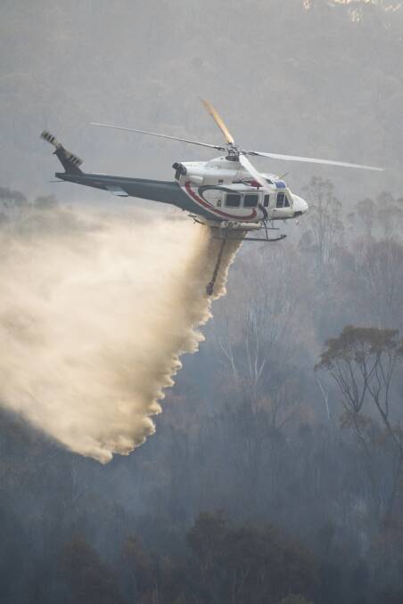 A helicopter drops water to slow the spread of the Orroral Valley fire earlier this month, as seen from Naas Road near Tharwa. Picture: Dion Georgopoulos