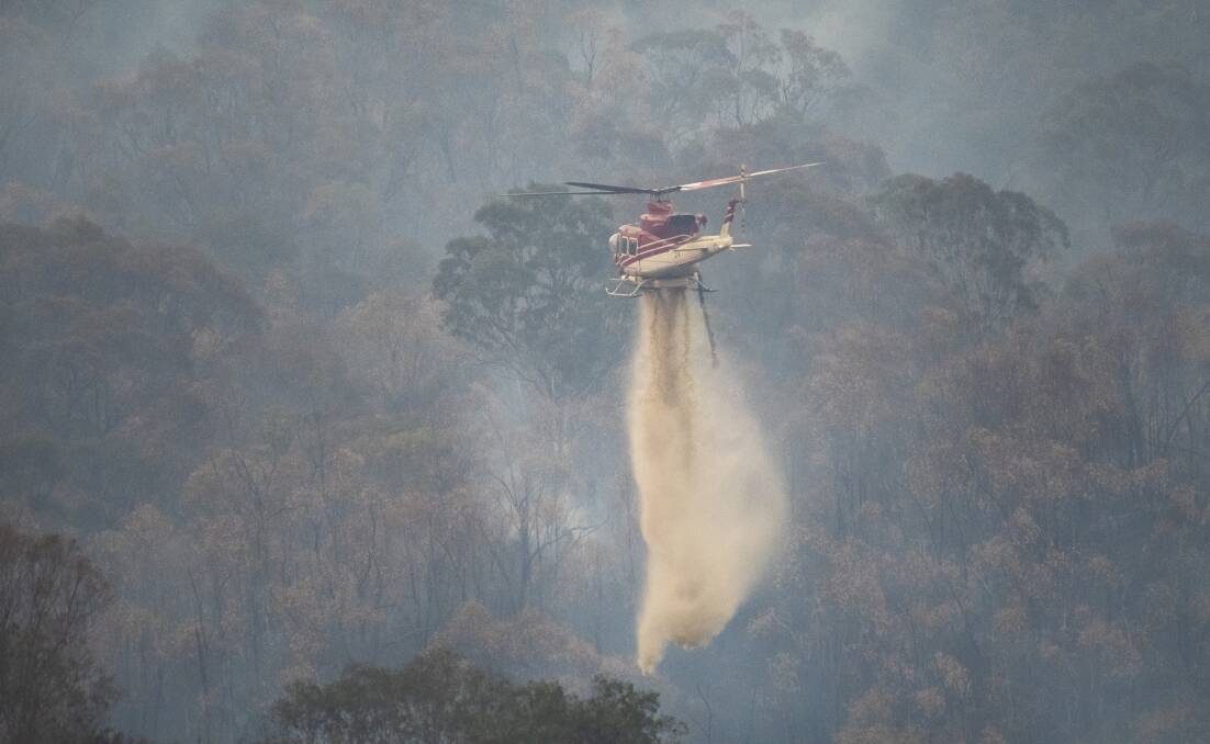 A helicopter drops water to slow the spread of the Orroral Valley fire, as seen from Naas Road near Tharwa on February 7, 2020. Picture: Dion Georgopoulos