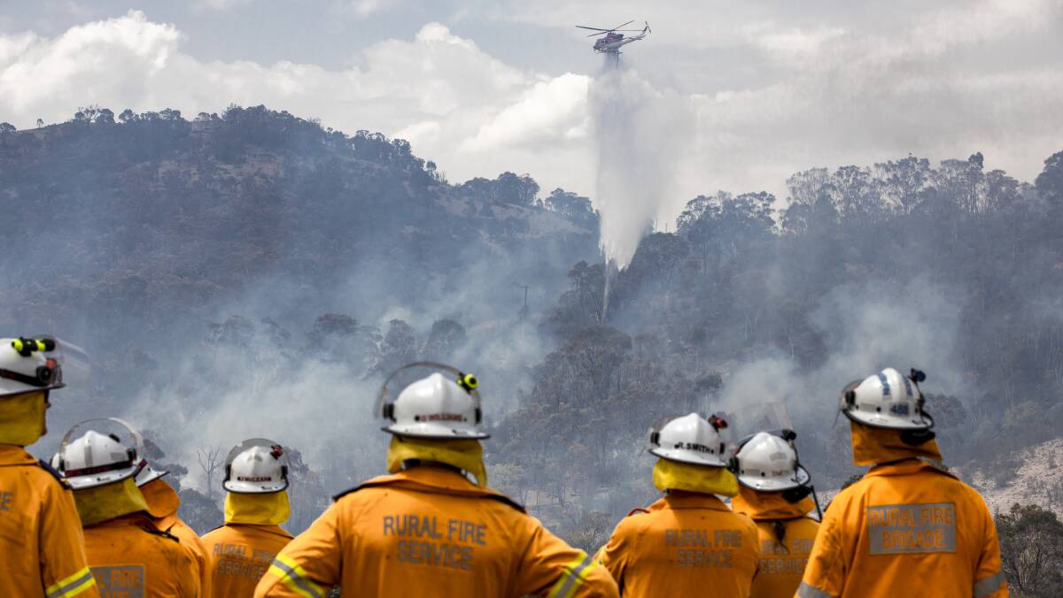 Firefighters watch a helicopter take on the Orroral Valley fire. Picture: Sitthixay Ditthavong