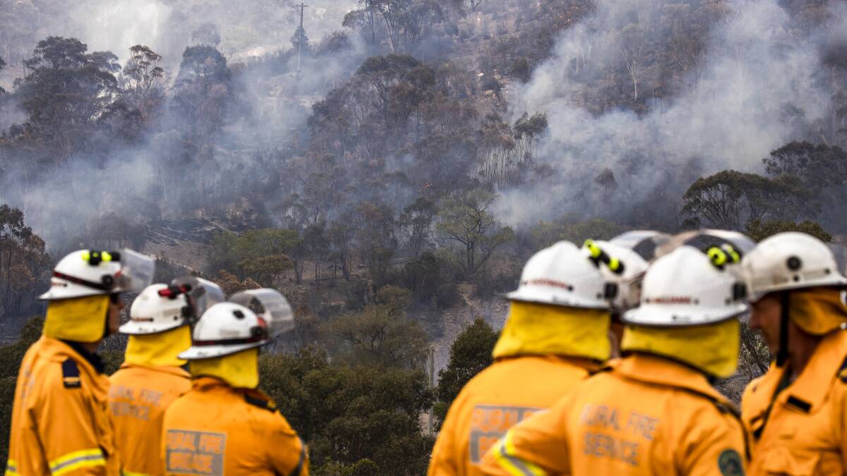 Fire crews watch the Orroral Valley fire threatening a property on Boboyan Road on Sunday afternoon. Picture: Sitthixay Ditthavong