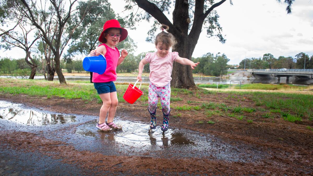 Sisters April Meere, 4, and Eva, 2, enjoy playing in puddles near Isabella Pond on Saturday. Picture: Elesa Kurtz
