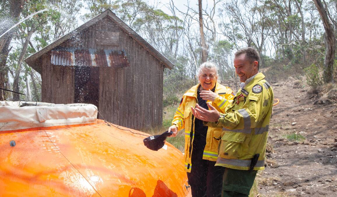 Emergency Services Agency commissioner Georgeina Whelan and ACT Parks manager Brett McNamara inspect the sprinkler system set up to protect historic Pryor's Hut. Picture: Department of Defence