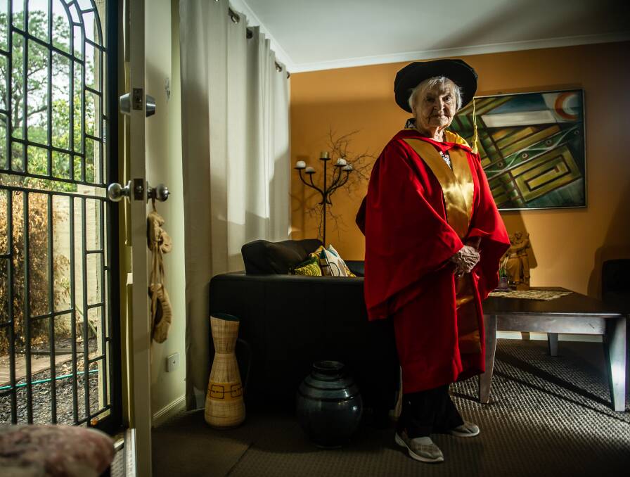 Skaidrite Darius, 92, this week in her O'Connor unit with the robes she wore when she received an honorary doctorate from the ANU. Picture: Karleen Minney,
